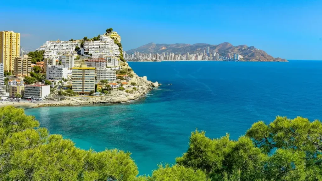 Vista panorámica de la costa de Benidorm con edificios frente al mar Mediterráneo y aguas turquesas.