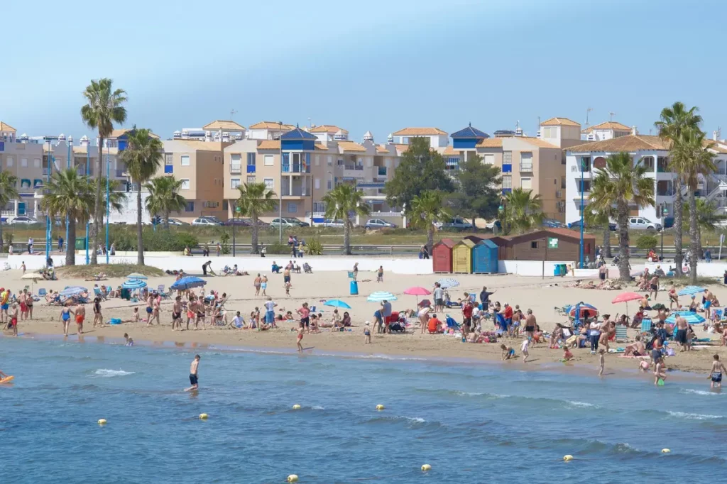Playa de Torrevieja con bañistas y edificios al fondo en un día soleado