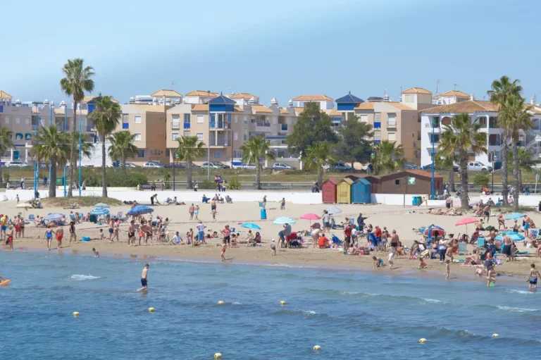 Playa de Torrevieja con bañistas y edificios al fondo en un día soleado
