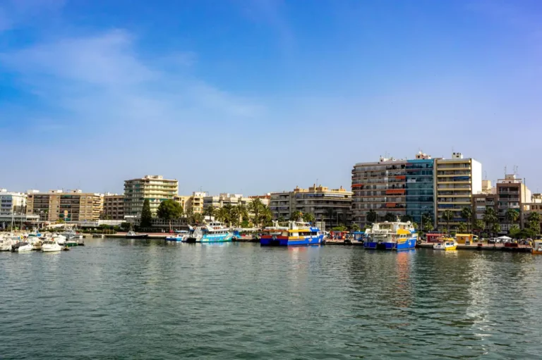 Puerto de Santa Pola con barcos y edificios junto al mar.